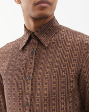 Load image into Gallery viewer, Close-up of a person wearing a brown patterned shirt with a plain background
